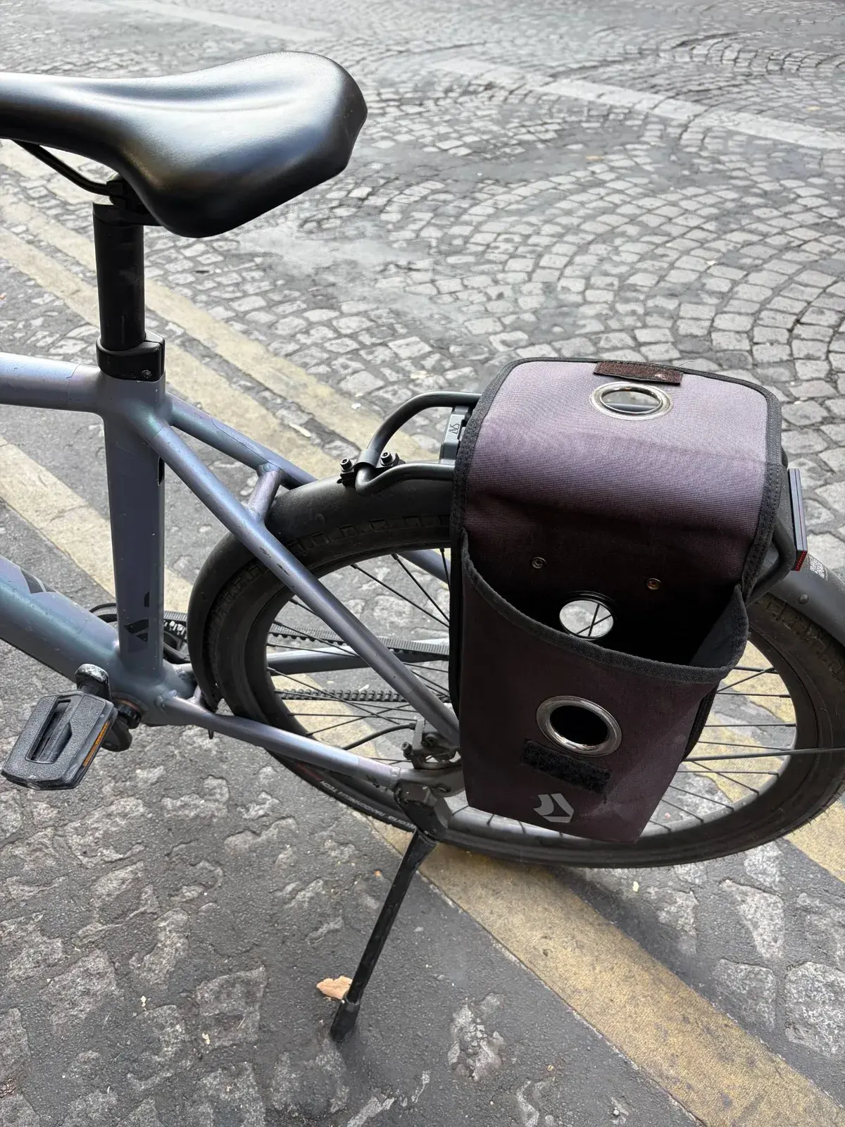 La sacoche arrière du vélo Dance, ouverte, fixée au porte-bagages au-dessus de la roue arrière, prévue pour ranger la chaîne antivol